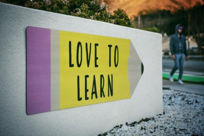 Photo by Tim Mossholder love to learn pencil signage on wall near walking man