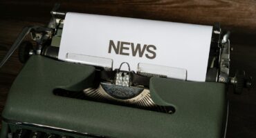 a close up of a typewriter with news paper on it