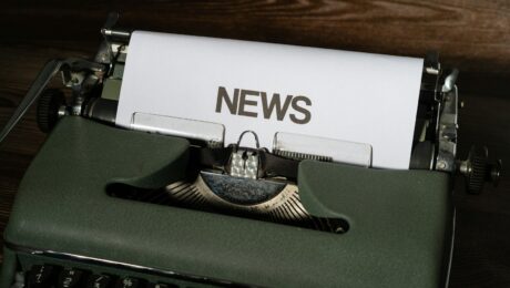 a close up of a typewriter with news paper on it