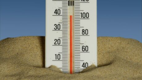 Photo by Immo Wegmann A thermometer in the sand with a blue sky in the background